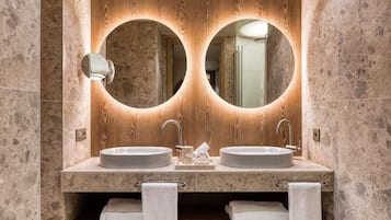 Baño con dos lavamanos, tocador de madera y espejo con iluminación circular.