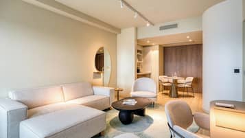 A modern living room with a sofa, armchairs, a coffee table, and a dining area with a table and chairs.