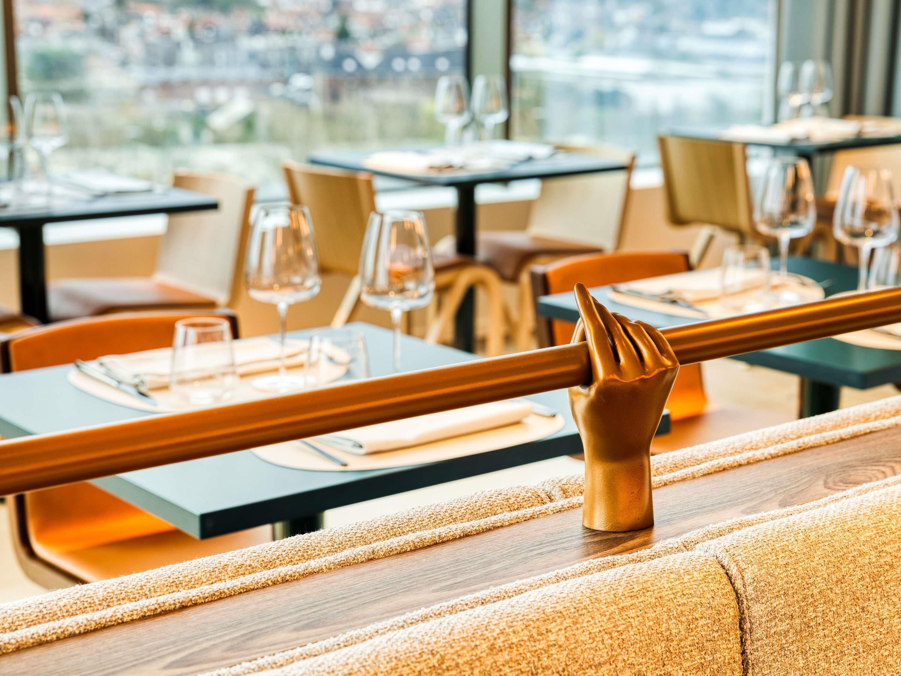 A restaurant interior with tables set for dining, chairs, and a view through the window.