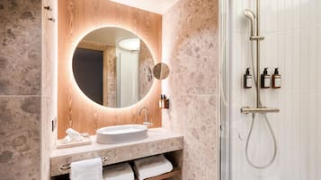 A modern bathroom with a round mirror, a sink, and a shower.