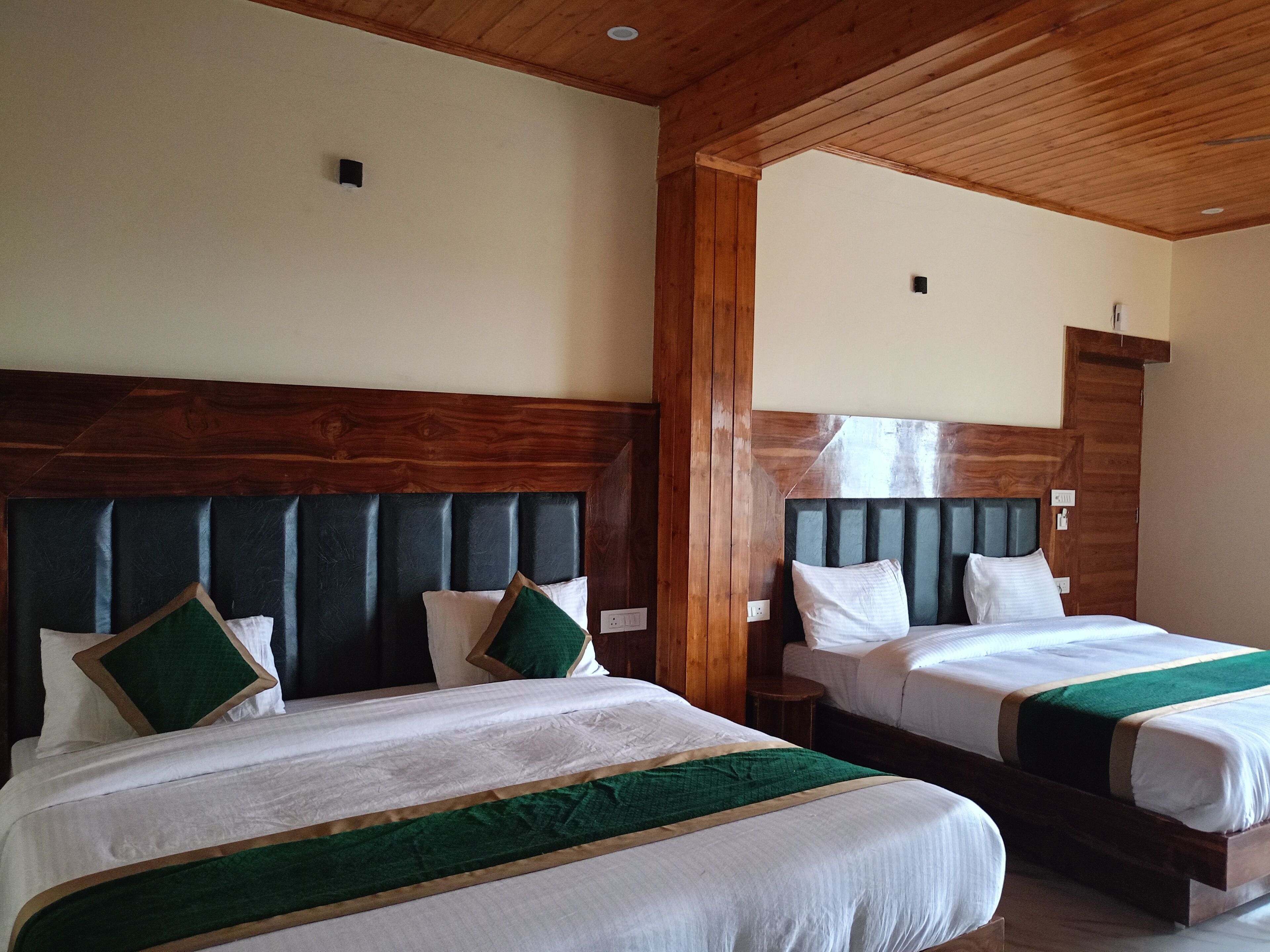 Ein Hotelzimmer mit zwei Betten, Holz Kopfteilen und einer Holzbalkendecke.