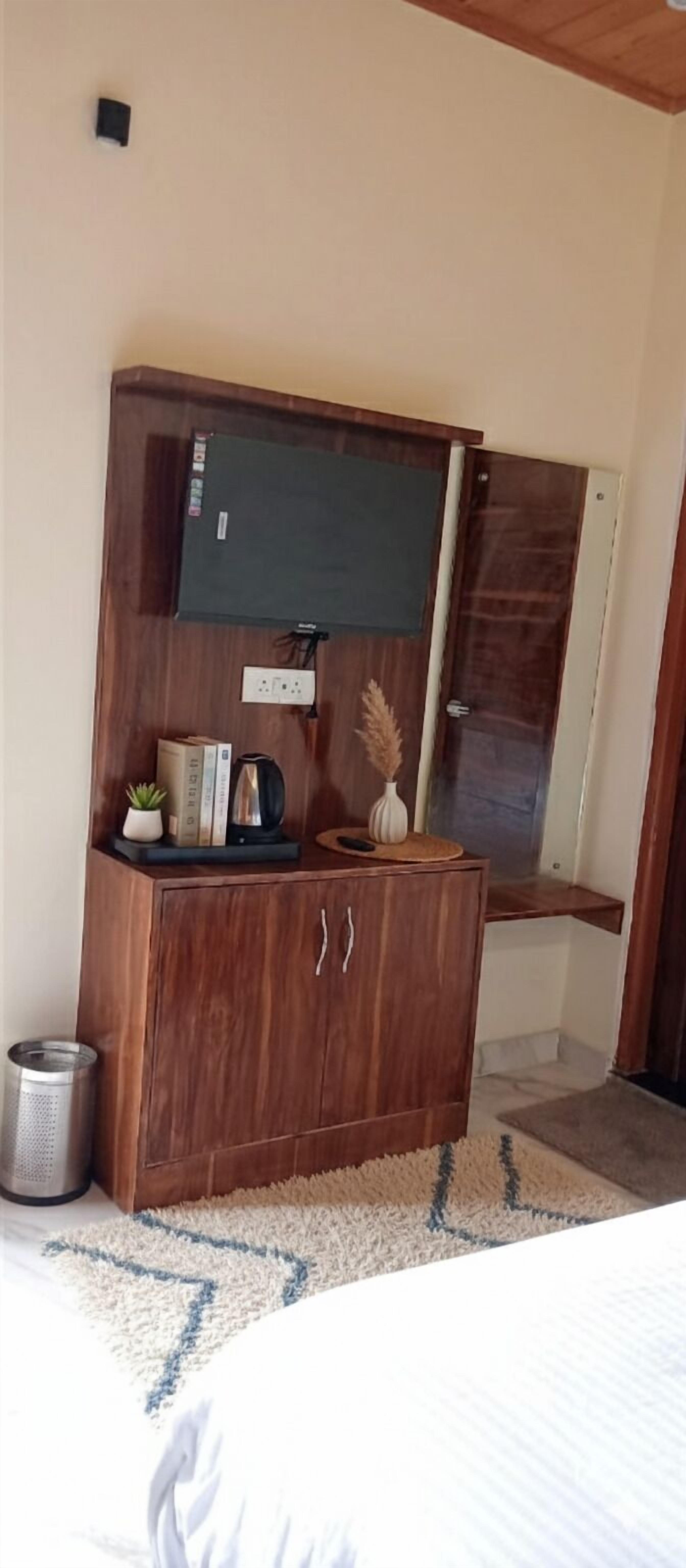 A wooden cabinet with a flat-screen TV, a small plant, books, and a vase.