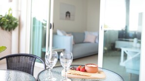 Une table en verre avec deux verres à vin, un bol de trempette et des crackers.