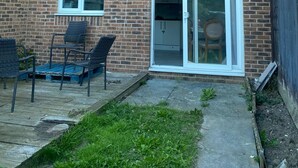 A brick apartment building with a small patio area, a sliding glass door, and a satellite dish. - Sittingbourne Serenity - Spacious 4-bed House (Sittingbourne)