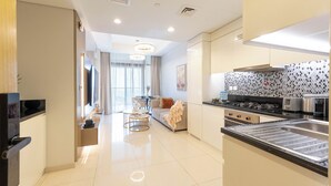 A modern kitchen with a large island, stainless steel appliances, and a dining area with a sofa and table. - Chic 2BR Urban Escape in Aykon City (Dubai)