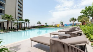 A poolside area with lounge chairs and a swimming pool. - Chic 2BR Urban Escape in Aykon City (Dubai)