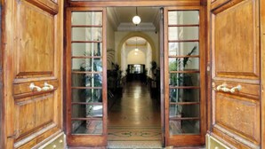 A grand wooden entrance with glass panels and a central archway leading to a hallway with potted plants.