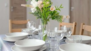 A dining table set with white plates, clear glasses, and a vase with flowers. - Elegancki i Stylowy Apartament Niedaleko Rynku w Poznaniu by Noclegi Renters (Poznan)