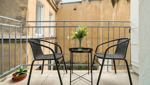 A small balcony with two chairs and a table, a potted plant, and a view of a building. - Elegancki i Stylowy Apartament Niedaleko Rynku w Poznaniu by Noclegi Renters (Poznan)