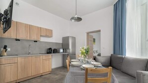 A modern kitchen with wooden cabinets, a dining table set for four, and a grey sofa in the living area. - Elegancki i Stylowy Apartament Niedaleko Rynku w Poznaniu by Noclegi Renters (Poznan)