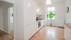Une cuisine moderne avec des meubles blancs, un four encastré et une plante en pot.