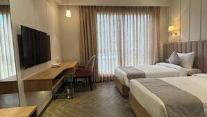 Habitación de hotel con dos camas, un escritorio, una silla, un televisor y un ventilador de techo.