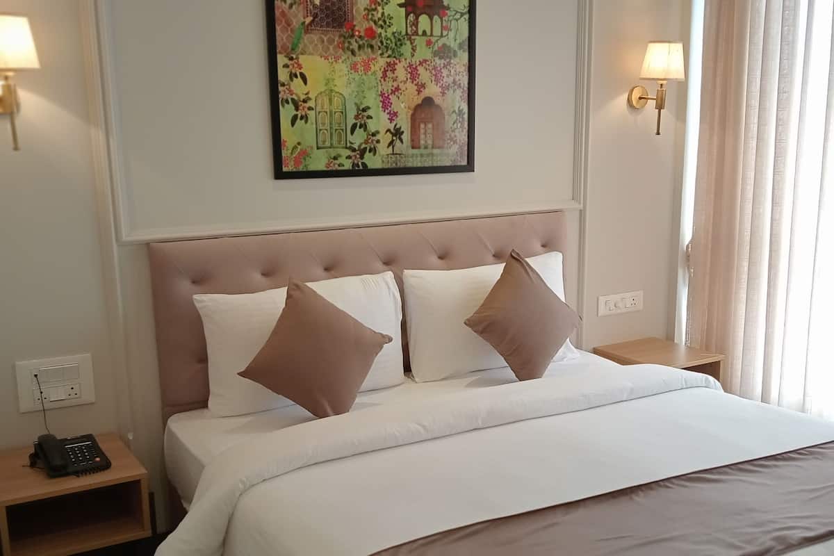 Ein Hotelzimmer mit einem großen Bett, einem Kopfteil, einem Nachttisch mit Telefon und einem Wandbild.