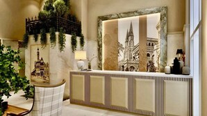 Zona de recepción con un cuadro grande enmarco de una catedral, un mostrador de recepción y una silla.