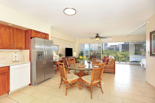 Una cocina moderna con refrigerador de acero inoxidable, armarios de madera y un comedor con sillas de mimbre y una mesa de vidrio.