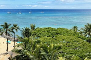 Una playa con palmeras, una orilla arenosa y barcos en el agua.