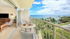 A balcony with a table, chairs, and a TV. - Gorgeous Ocean View Suite at Waikiki Shore! Steps to Beach! Heart of Waikiki! (Honolulu)