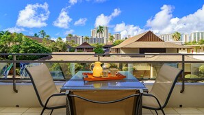 A balcony with a table, chairs, and a tray with a pitcher and cups.