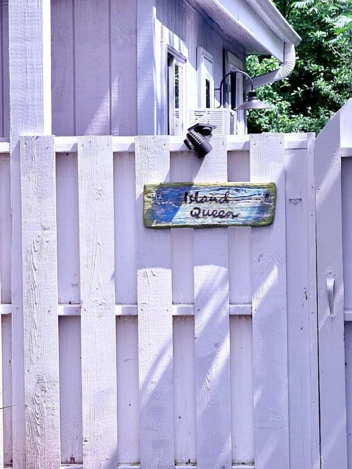 A white picket fence with a sign that reads 'Island Queen.'