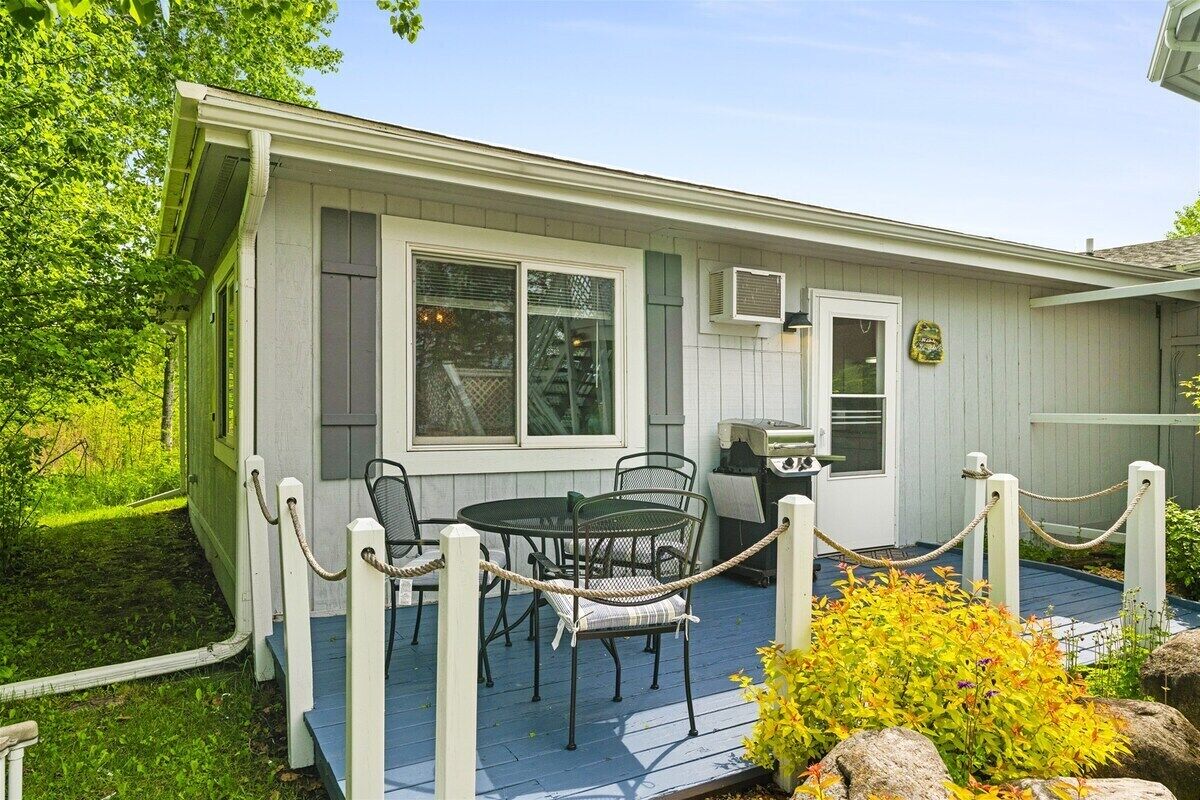 Une maison avec une véranda, un barbecue et une table à manger avec des chaises.