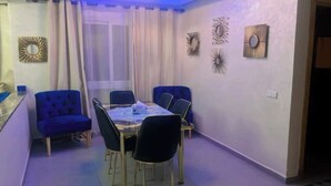 Un coin repas comprenant une table ronde, quatre chaises et des œuvres d’art décoratives accrochées au mur.