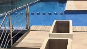 Une piscine intérieure avec des marches menant à l’eau, entourée d’un bâtiment doté de nombreuses fenêtres et d’un escalier en colimaçon.