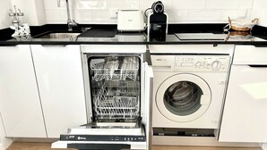Een keuken met een vaatwasser, een wasmachine, een broodrooster en een gootsteen.