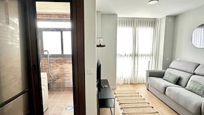 A living room with a sofa, a TV, and a wooden floor.