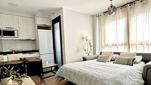 Une chambre à coucher moderne avec un grand lit, une table de chevet, une lampe et une vue sur l’extérieur par une fenêtre.