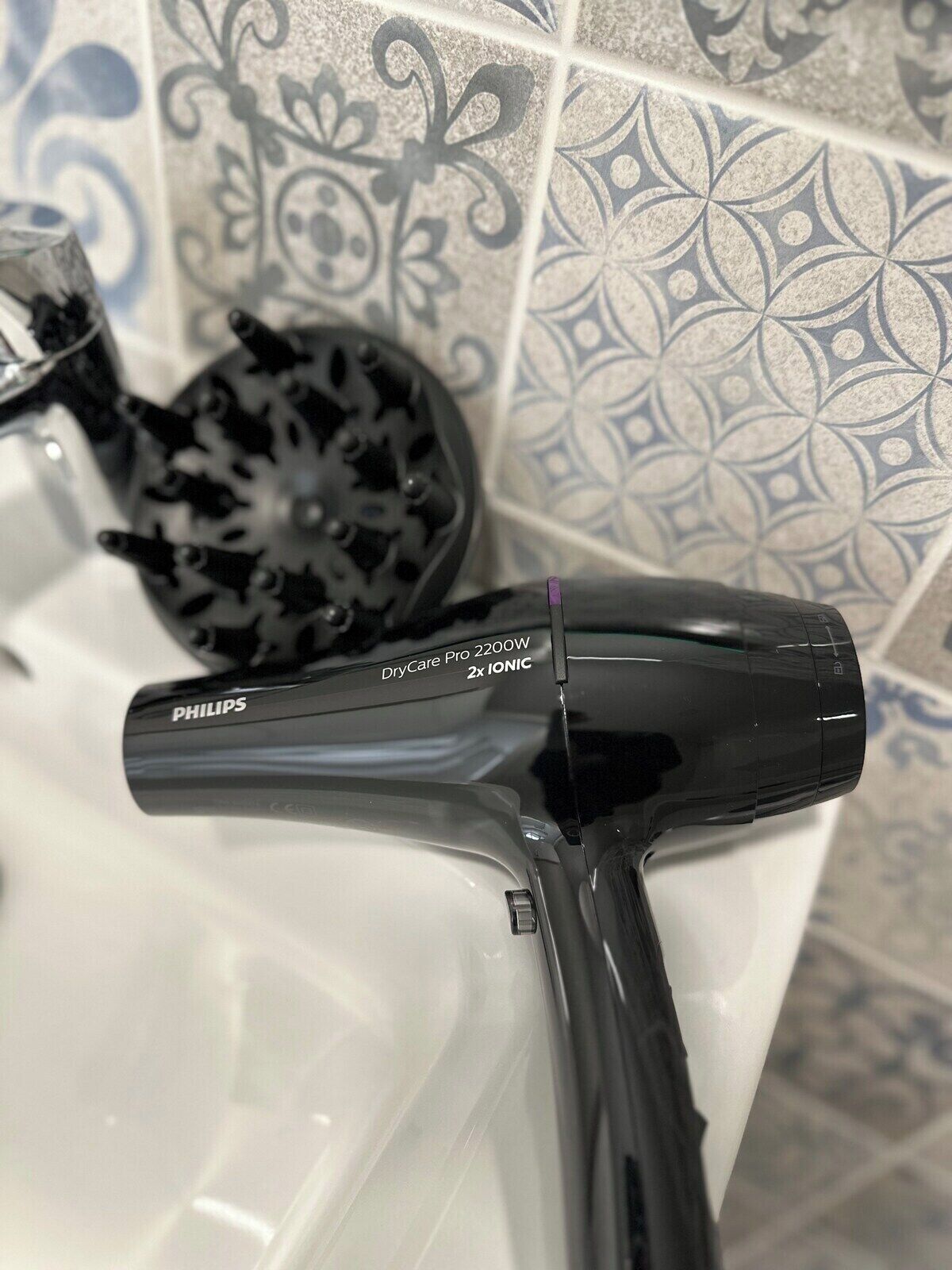 A Philips hair dryer in a bathroom with patterned tiles.