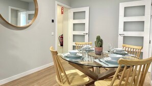 En matplats med ett runt bord i glas, trästolar och en kaktus som står på bordet.