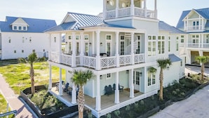 A multi-story house with a balcony, a covered porch, and a view of the surrounding area. - Gulf View/Crow’s Nest@Cinnamon Shore South 4-BR Home w/Pools & Amenities (Port Aransas)