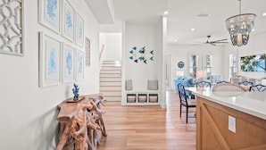 Una cocina moderna con una isla de madera, paredes blancas y obras de arte enmarcadas.