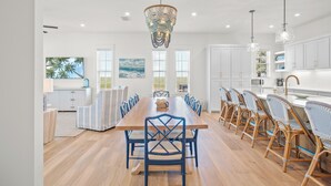 Un comedor espacioso con una larga mesa de madera, sillas azules y un candelabro decorativo.