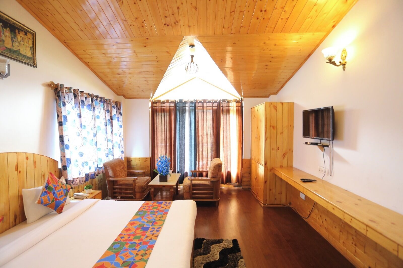 A cozy room with a bed, a desk, a TV, and a dining area.