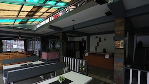 Un restaurante con techos altos, bancos de madera y techo verde.