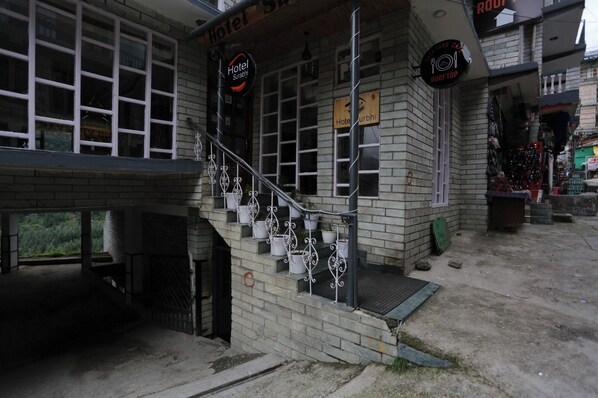 Un hotel con una escalera que conduce a la entrada, rodeado de muros de ladrillo y plantas en macetas.