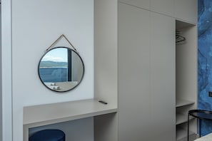 A modern bathroom with a round mirror, a small sink, and a towel rack.