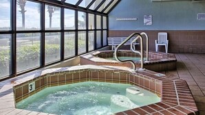 Un espace avec un bain à remous doté d’un toit en verre, une piscine et un banc.