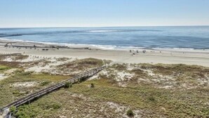 Une plage avec une promenade en bois menant au rivage, une plage de sable et l’océan.