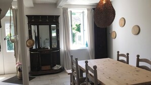 Uma área de refeições com uma mesa e cadeiras de madeira, um lustre pendente e um espelho sobre o balcão.
