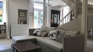Uma sala de estar com sofá, mesa de centro, escada e estante de livros.