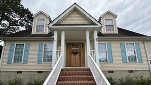 A two-story house with a front porch, a wooden front door, and a brick staircase leading up to the entrance. - Cottage on Snug Harbor, minutes from O.C. beaches, Berlin, and Assateague.  (Berlin)