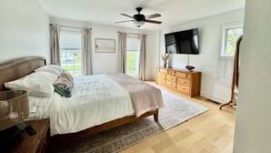 A bedroom with a bed, a ceiling fan, a TV, a dresser, and a window with curtains. - Cottage on Snug Harbor, minutes from O.C. beaches, Berlin, and Assateague.  (Berlin)