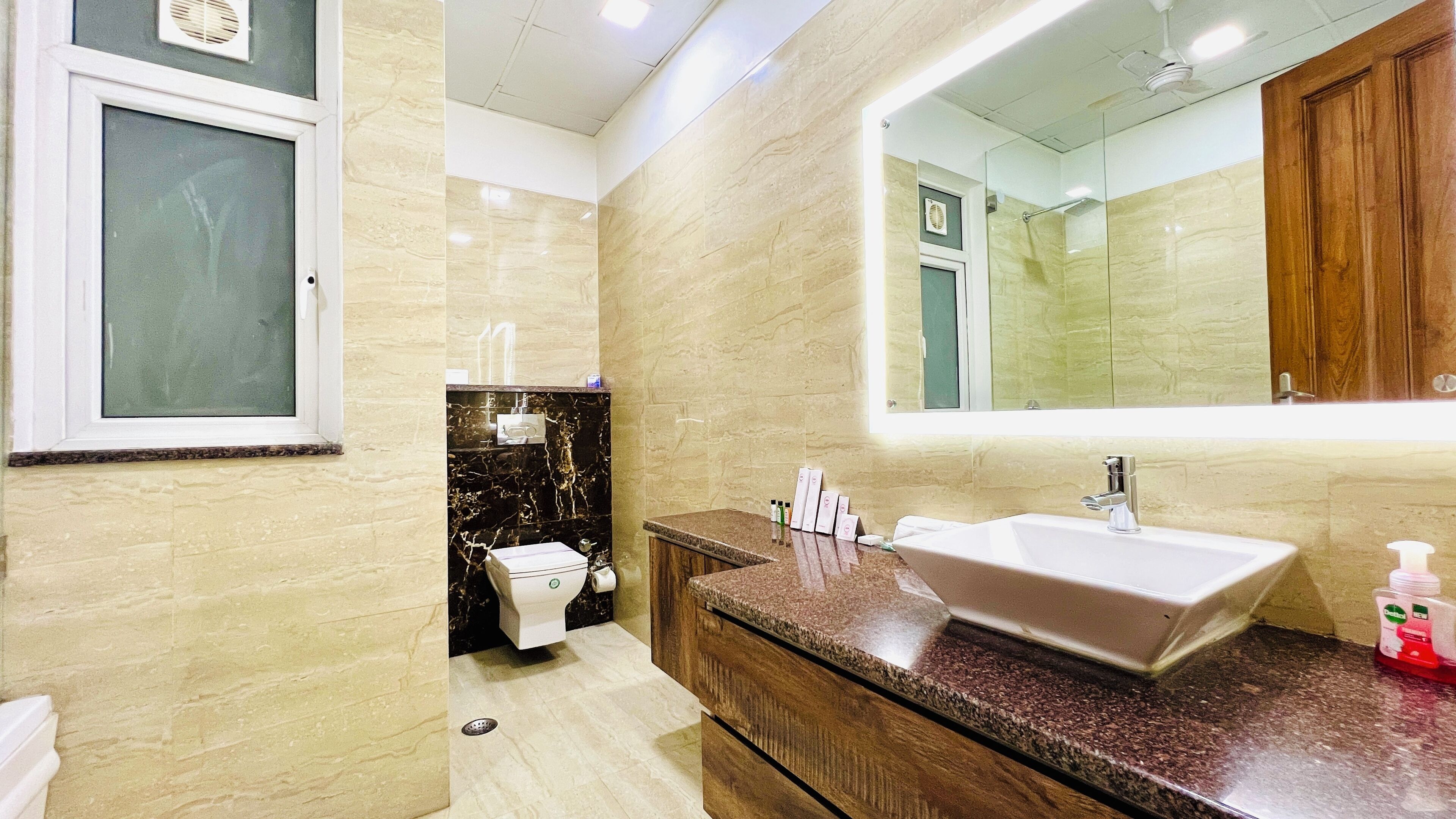 A modern bathroom with a large mirror, a marble vanity, and a shower area.