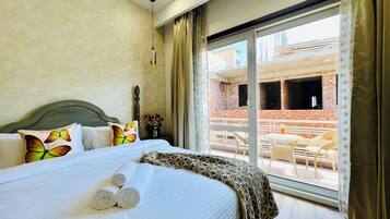 A hotel room with a bed, a window with a view of a balcony, and a door.