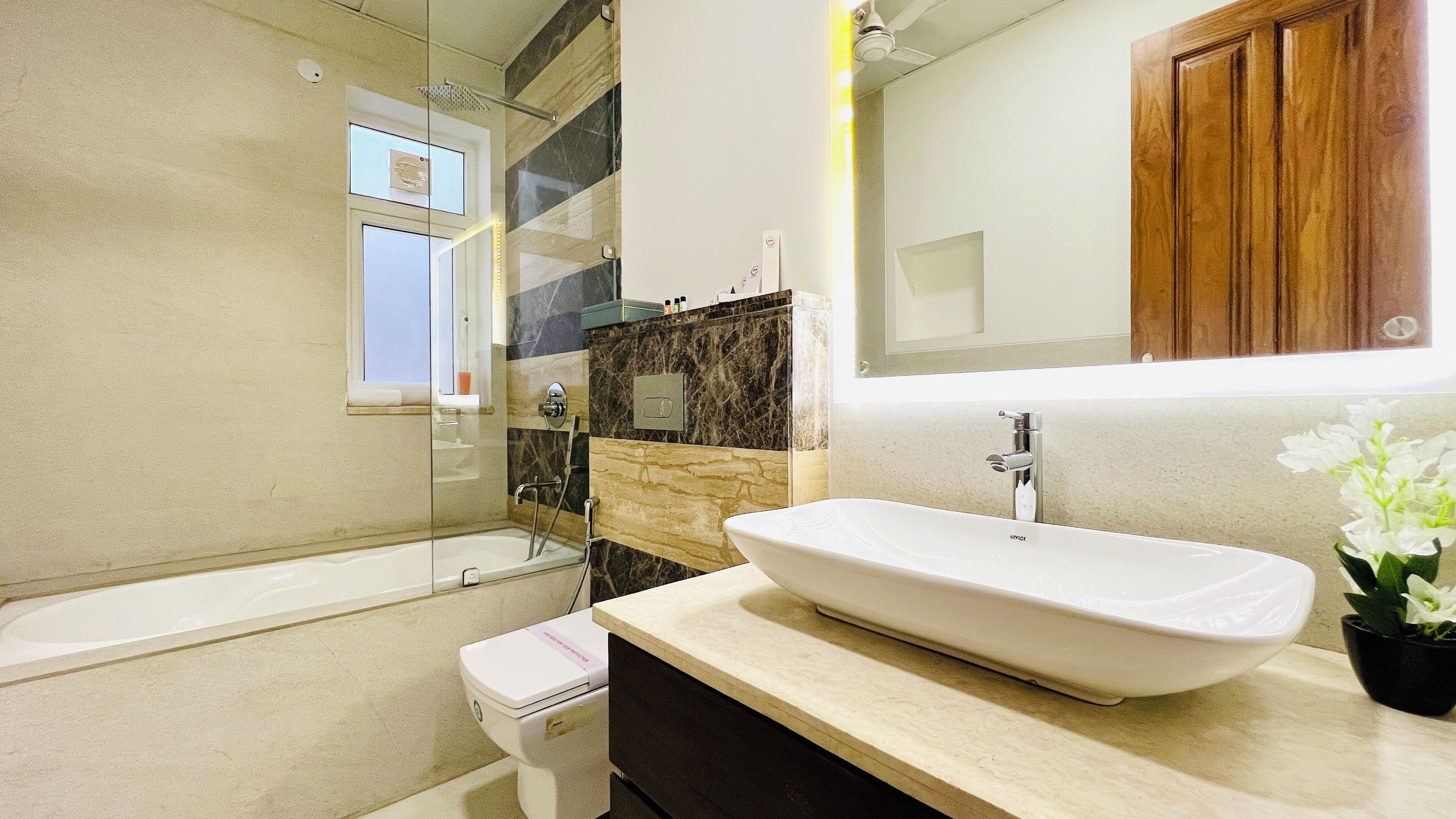 A modern bathroom with a large bathtub, a white sink, and a mirror above the sink.