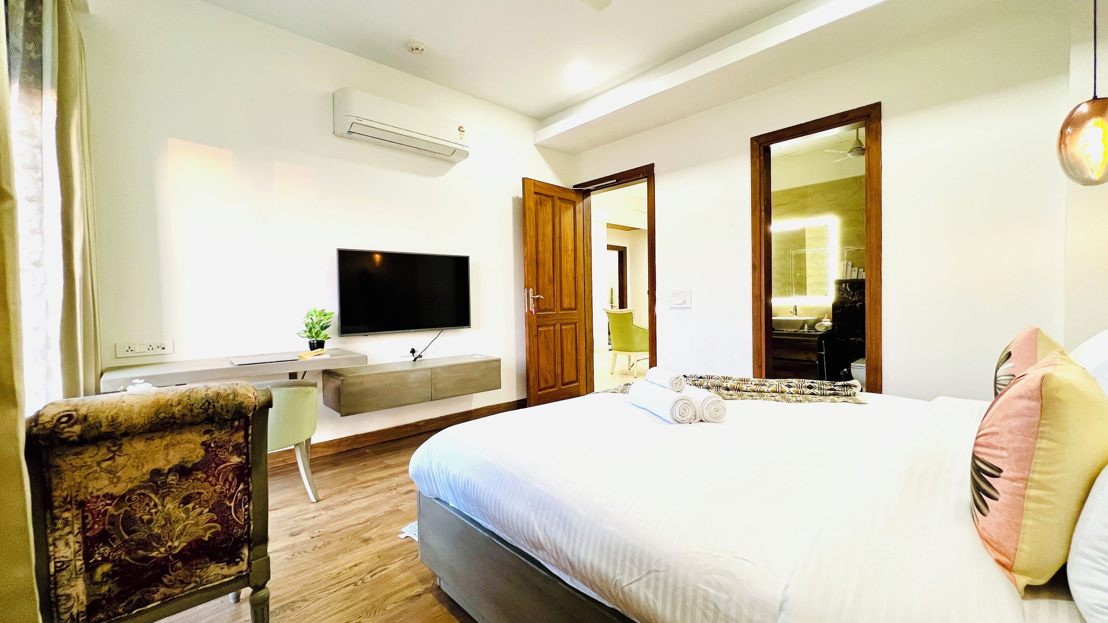 Habitación de hotel con una cama grande, televisión, escritorio y baño visible a través de una puerta abierta.