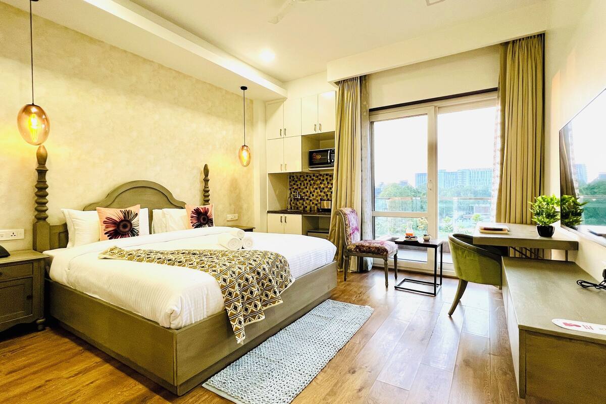 A hotel room with a bed, desk, chair, and a large window with a view.