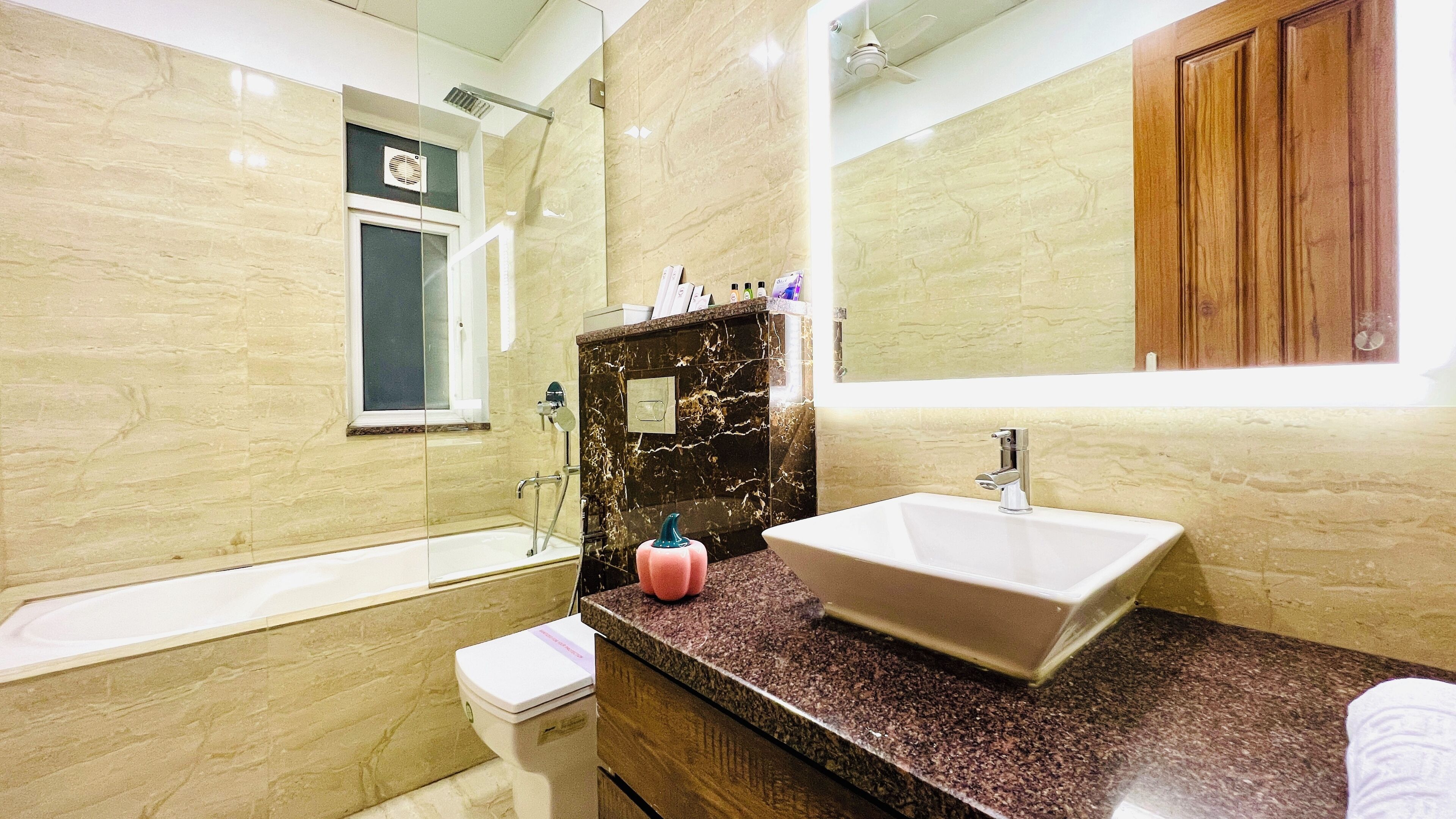 A bathroom with a marble wall, a bathtub, a sink, and a mirror.